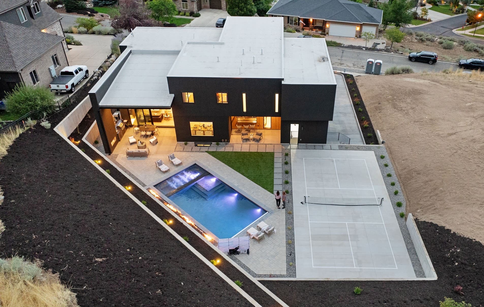 Aerial dusk view of a modern home with pool and sport court