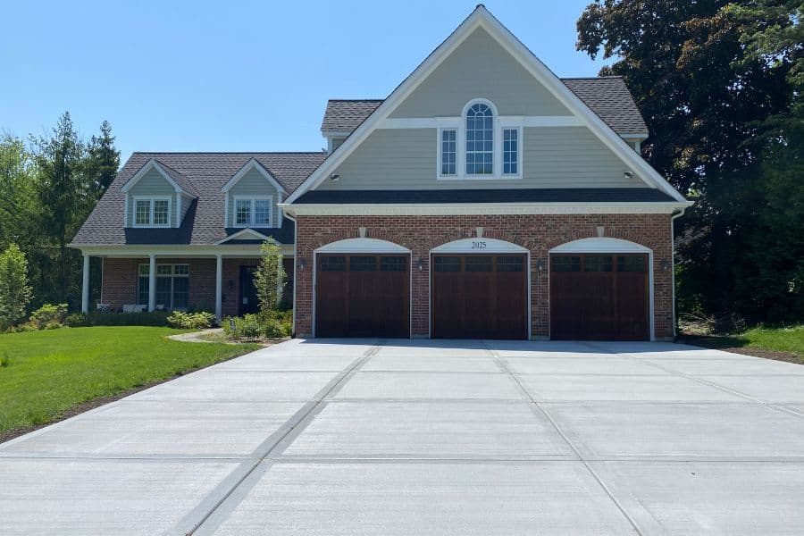 Finished concrete driveway leading to a three-car garage