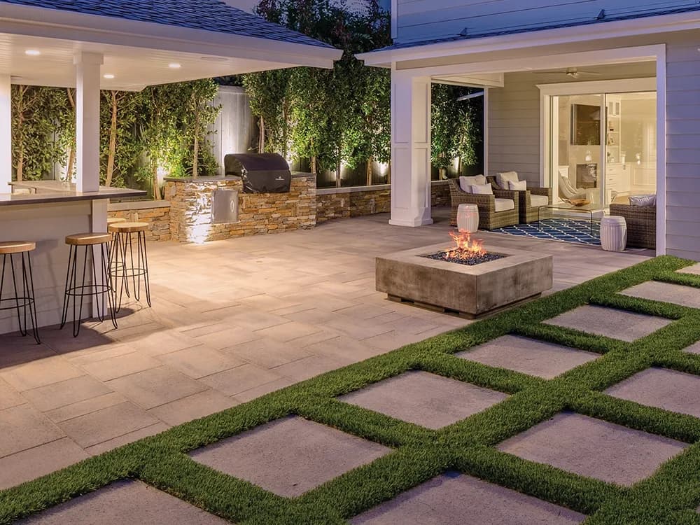 Outdoor kitchen with grill island and bar seating on a paver patio