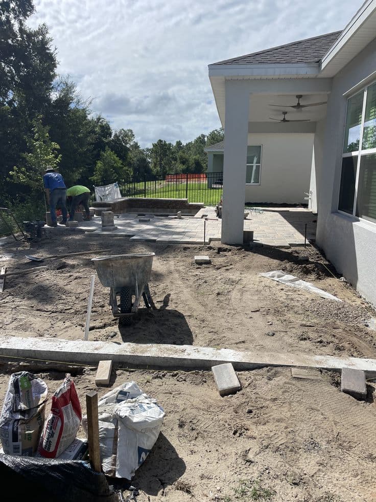 Landscape design-build crew constructing a paver patio behind a covered porch