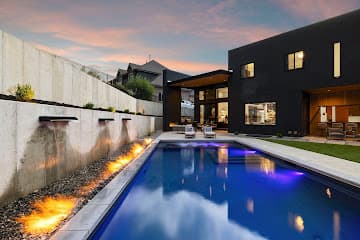 Engineered retaining wall with integrated fire-and-water feature beside a pool